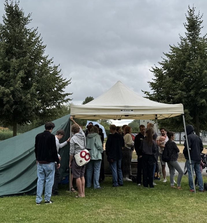 Mitglieder des Inselkiez unter einem Pavillon im Regen